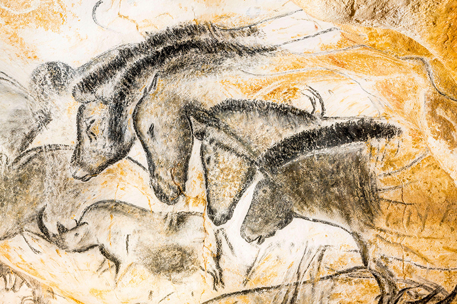 Dibujo de líneas negras de cuatro caballos de cuello para arriba en la pared de una cueva amarilla.