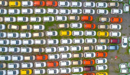 Vista aérea de un estacionamiento repleto de autos eléctricos de color blanco, dorado, amarillo y rojo.