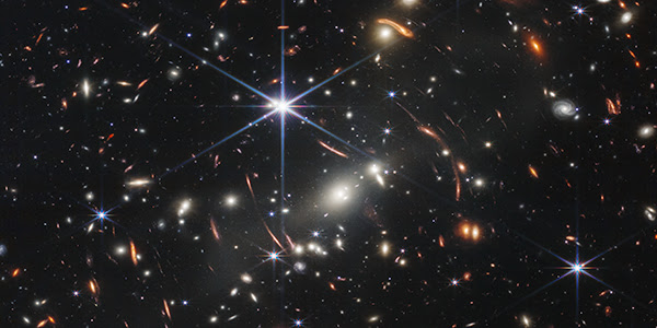 Thousands of bright galaxies are visible in the darkness of space in a processed image originally captured using a near-infrared camera focused on the galaxy cluster SMACS 0723. 