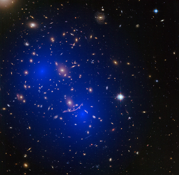 Imagen del telescopio espacial Hubble que muestra un conjunto de galaxias. Dos áreas sombreadas en azul muestran el lugar donde los científicos han detectado concentraciones de masa invisible dentro del cúmulo, que se cree que es materia oscura.