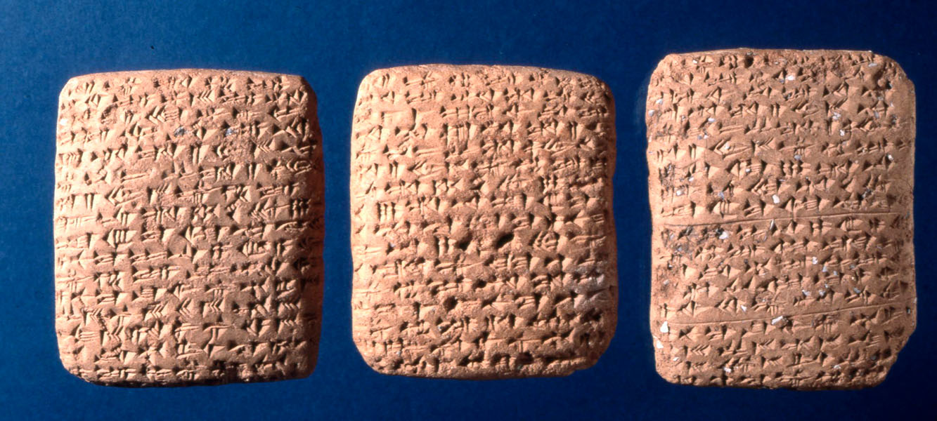 Fotografía de tres tablillas de arcilla cubiertas con letras cuneiformes.