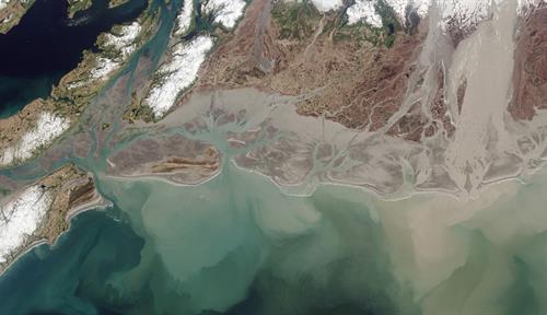 Una imagen aérea del río Copper desembocando en el Golfo de Alaska, vertiendo nubes de sedimentos en el mar.