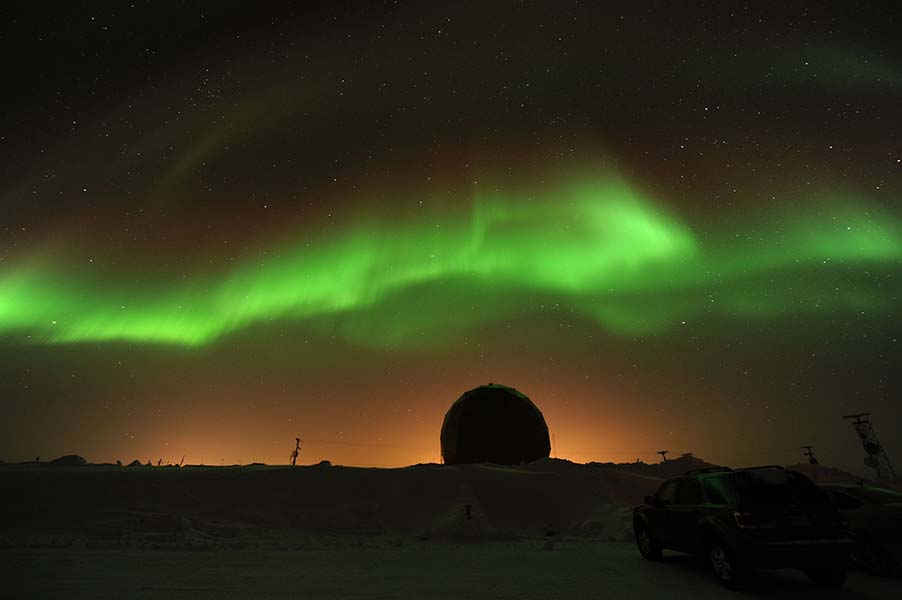 Imagen en la que se muestra el resplandor verde de la aurora boreal sobre un paisaje nocturno.
