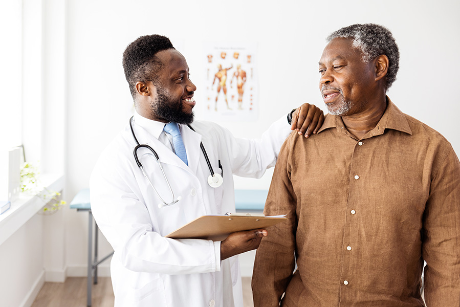 Foto de un anciano negro hablando con un médico negro más joven.