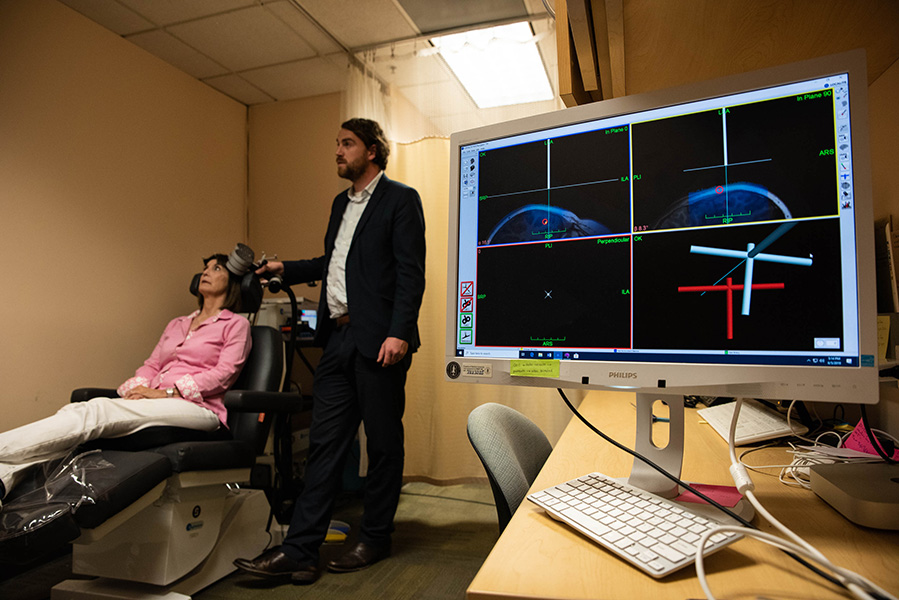 Foto del neurocientífico Nolan Williams sosteniendo un dispositivo de EMT.
