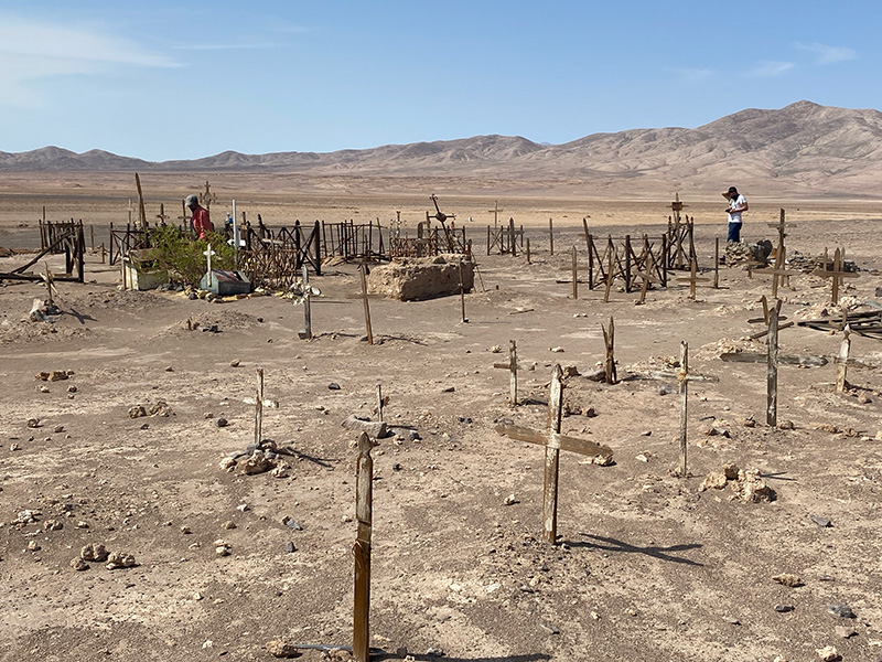 Un pequeño y austero cementerio con cruces de madera lisas y algunas vallas viejas se encuentra en el desierto