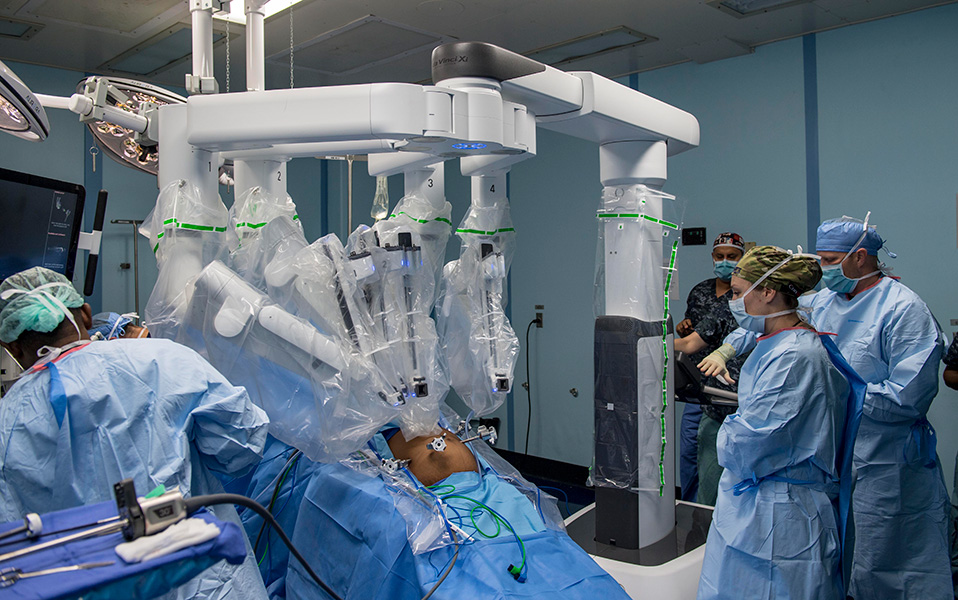 En medio de una sala de operación se observa el abdomen descubierto de un paciente que está siendo operado por una má
