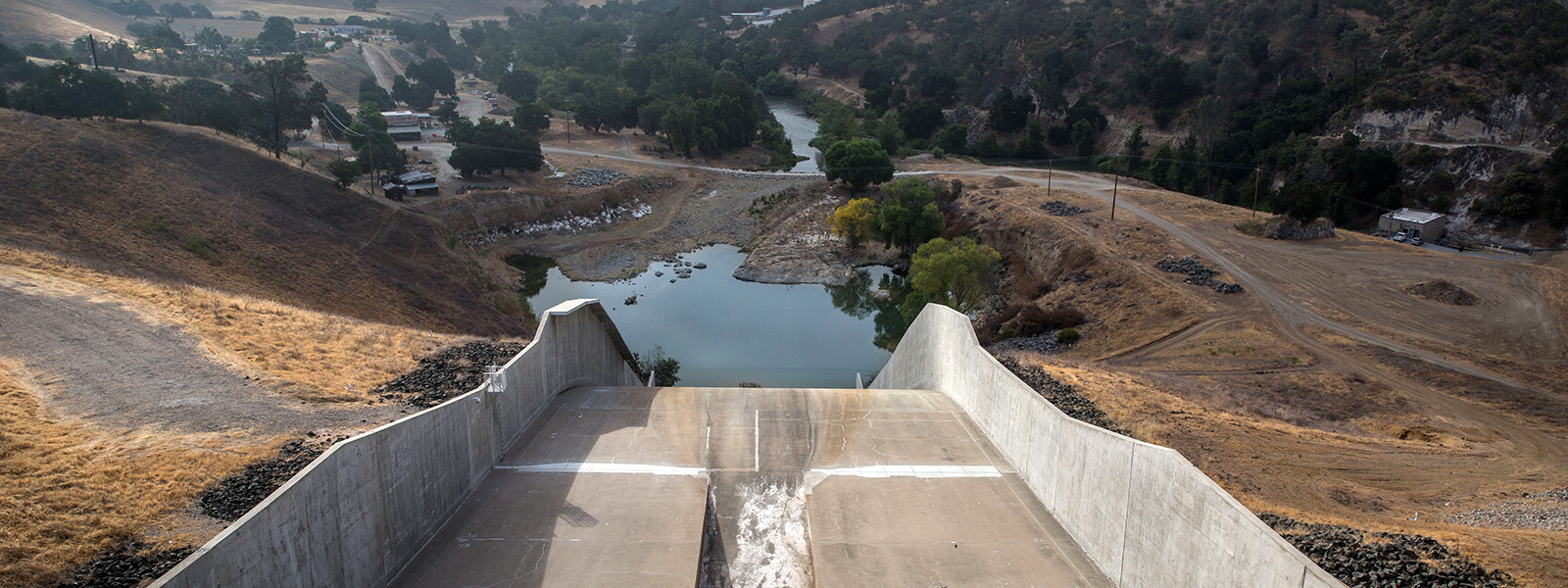 Photograph of a long concrete chute running into a reservoir that doesn’t seem to have much water in it!