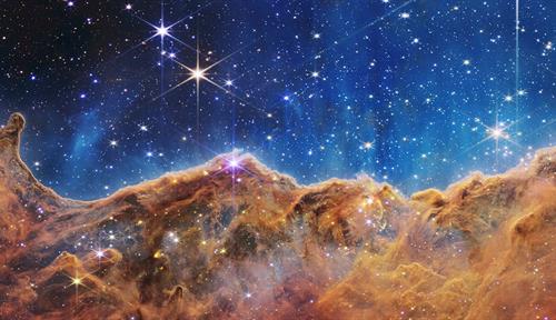 Imagen que muestra una vista profunda del universo, incluidas muchas galaxias que están lo suficientemente lejos como para parecer estrellas, sobre las nubes de color rosa de una nebulosa cercana que domina el primer plano.