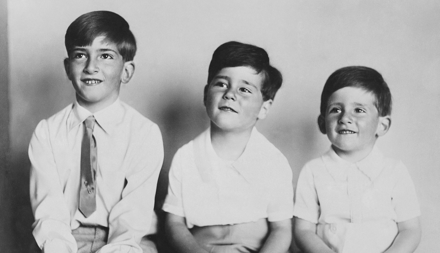Tres hermanos pequeños, sentados uno junto al otro, reflejan el parecido familiar.