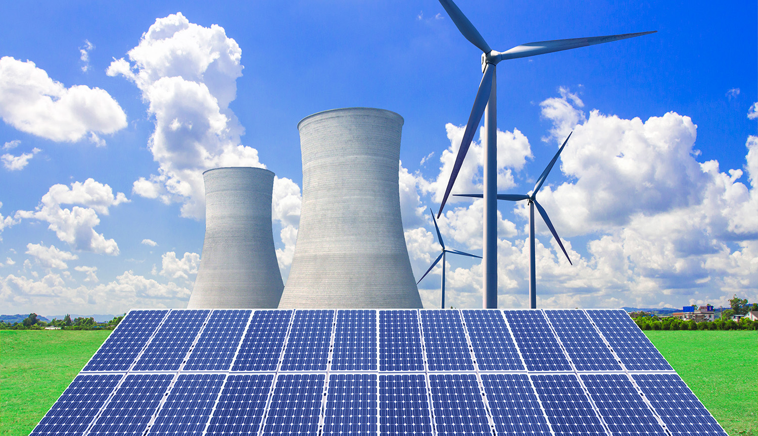 Las torres de refrigeración de una central nuclear, junto a molinos eólicos, se elevan sobre una serie de paneles solares.