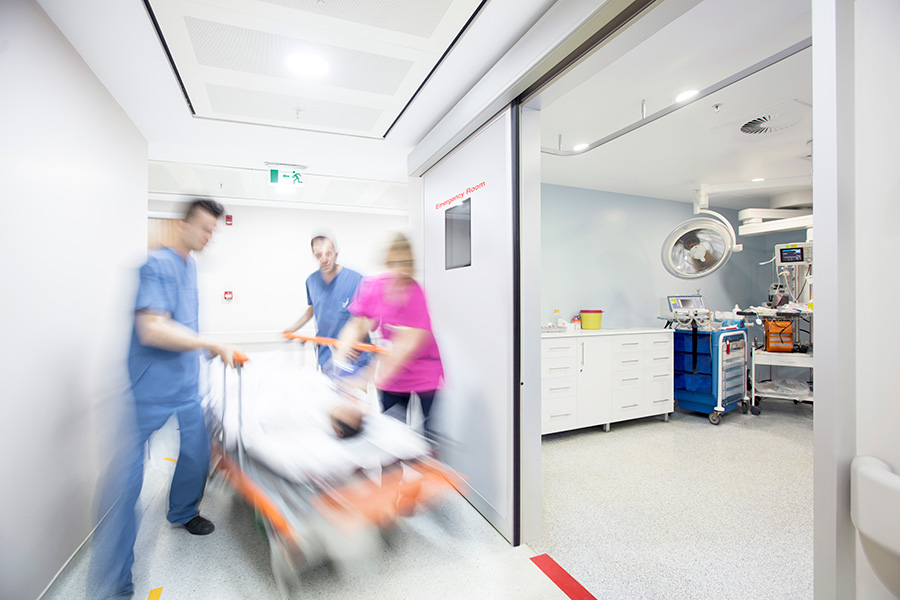 Foto borrosa de médicos y enfermeras trasladando a un paciente en una camilla en un hospital.