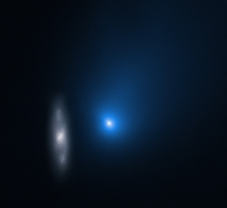 Un punto azul difuso con un centro blanco con una tenue galaxia grisácea a su izquierda sobre un fondo negro.