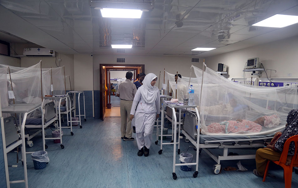 En una sala, los pacientes yacen en camas cubiertas con mosquiteros, mientras los trabajadores sanitarios los atienden.