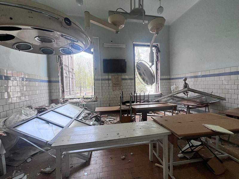 Daños colaterales Un quirófano destrozado, lleno de equipos rotos y escombros.