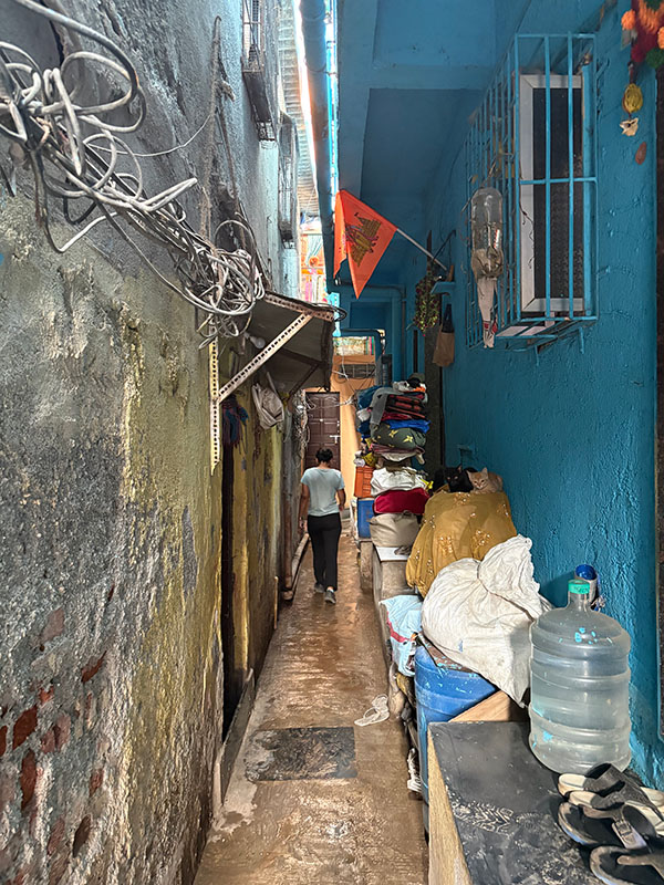 Un niño, visto de espaldas, camina por un callejón estrecho entre dos edificios.