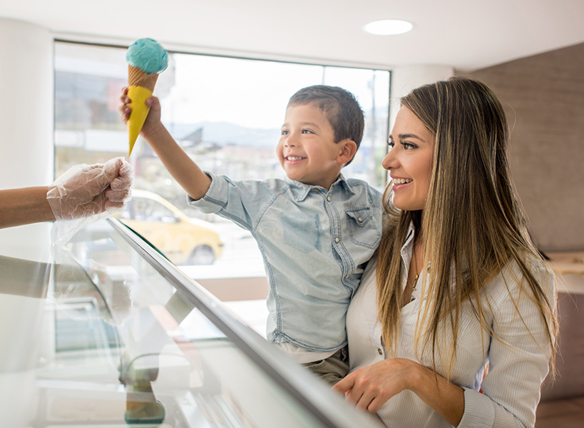 Un niño feliz en brazos de su madre toma un helado.