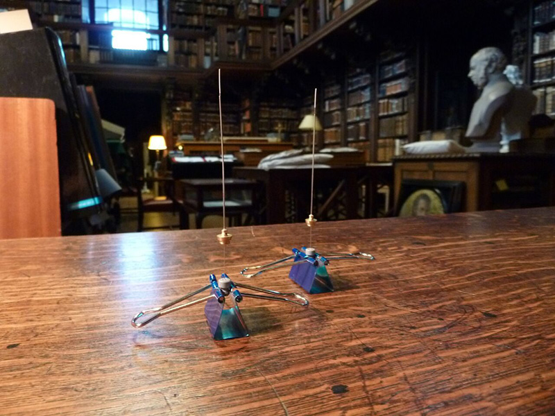 Analizando el aire Dos instrumentos delgados para la toma de muestras de aire sobre una mesa de madera en una biblioteca histórica.