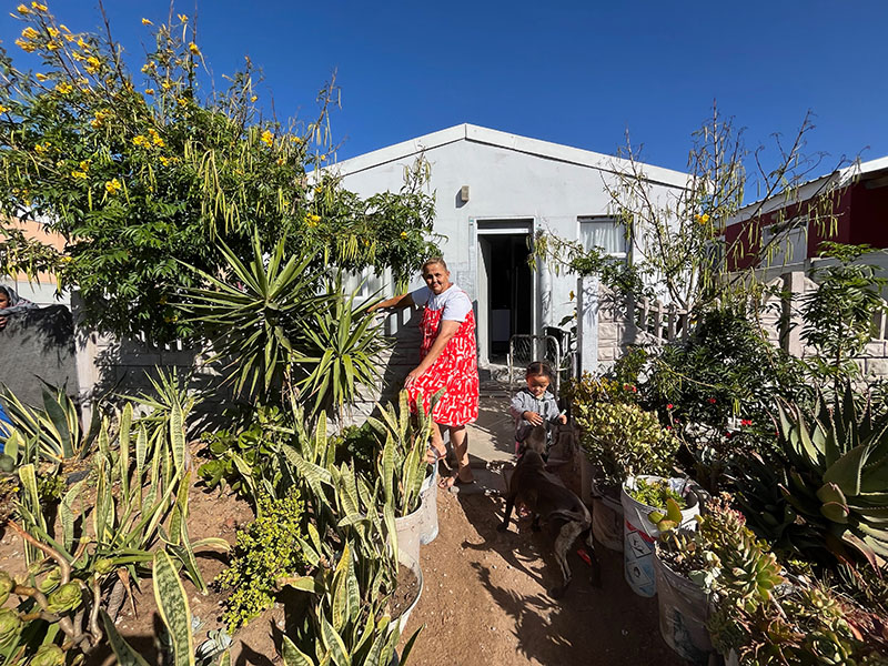 Fotografía de una mujer con un vestido rojo de pie en su jardín.