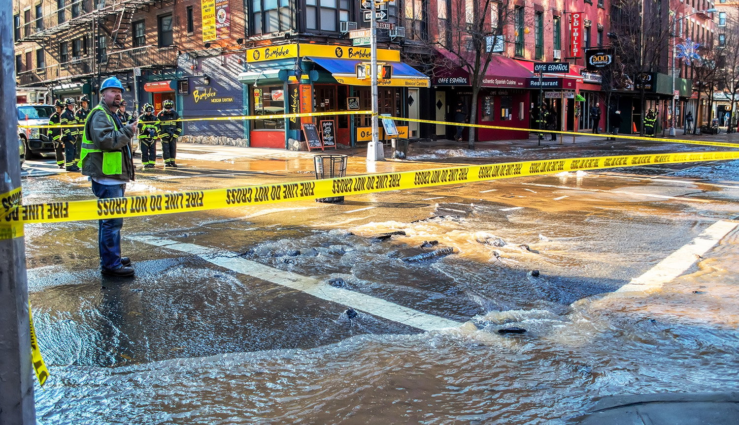 Foto muestra una intersección inundada y cerrada al tráfico con cinta amarilla de precaución en Nueva York.