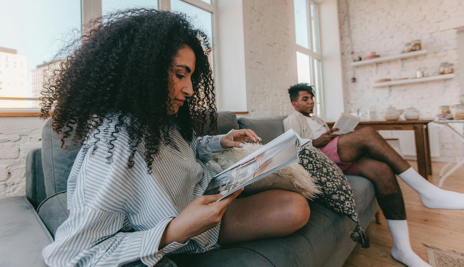 Una pareja sentada en un sofá. Están leyendo tranquilamente.